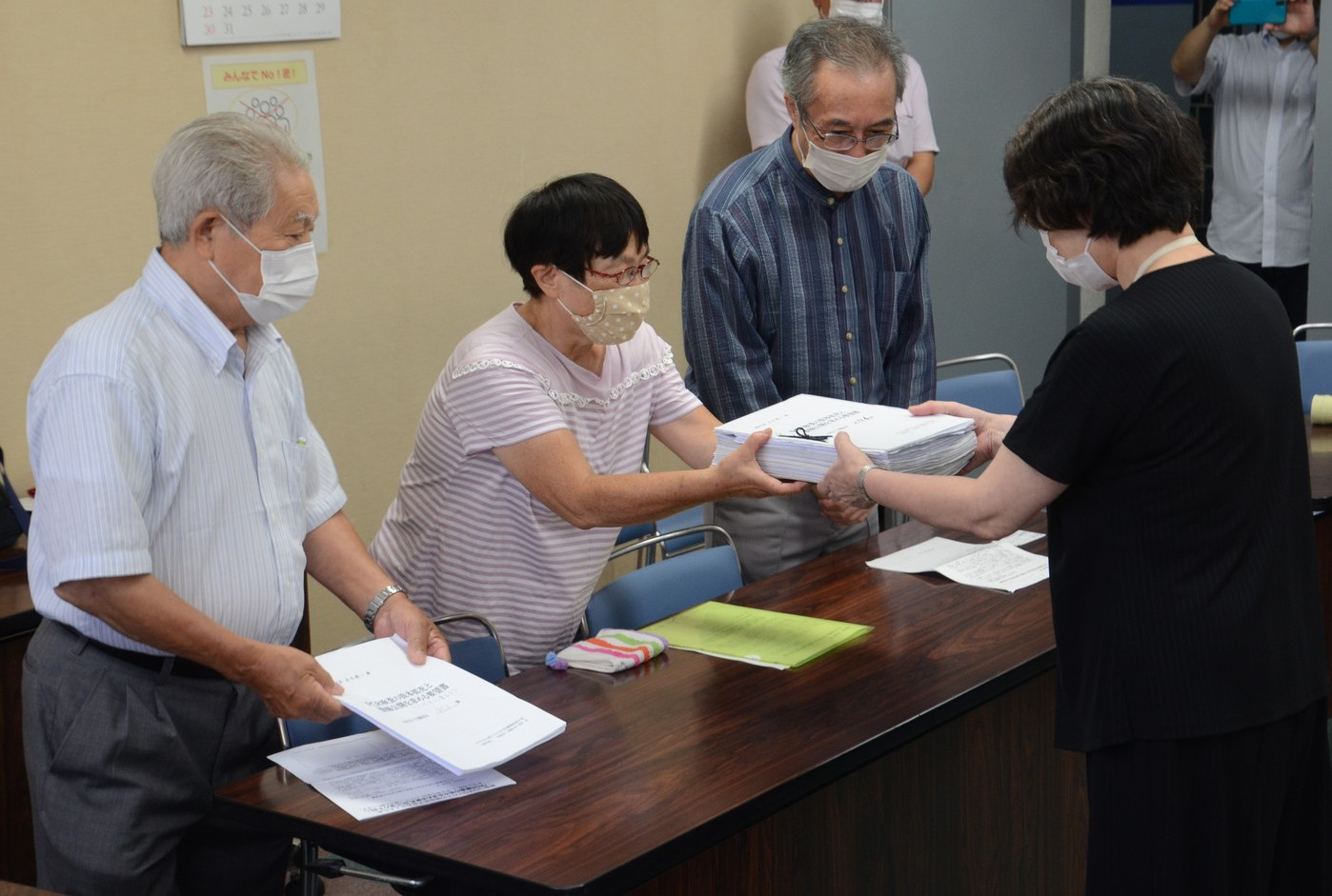 新宿区健康部長（右）に署名を提出する人たち