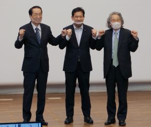参加者の声援にグータッチで応える（左から）菅、宮本、広渡の各氏